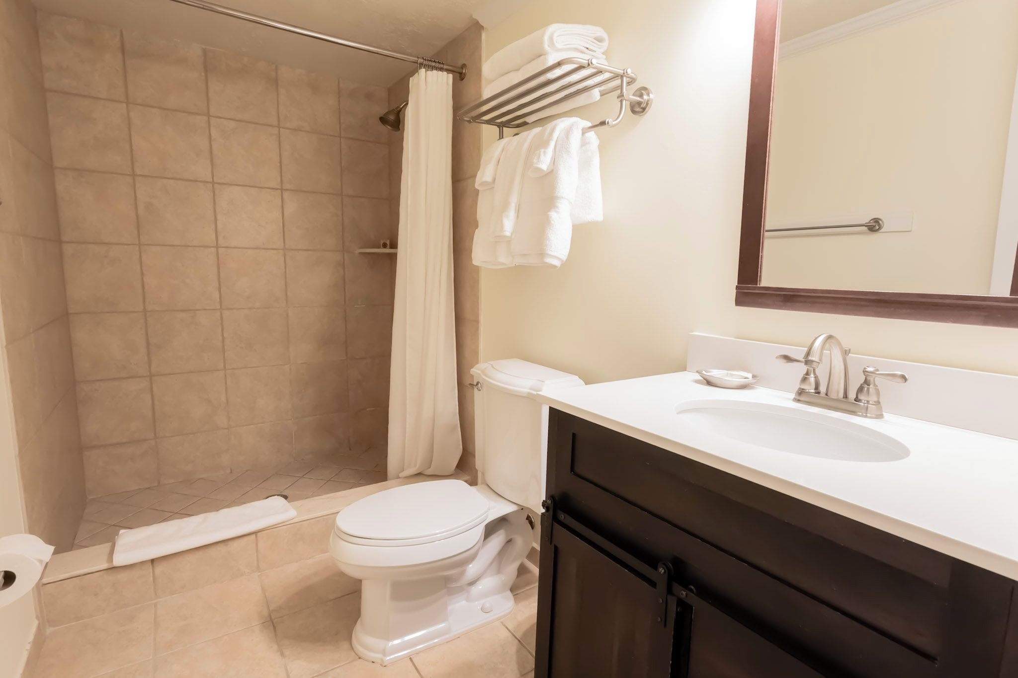Un baño con ducha, inodoro, lavabo y toallero.