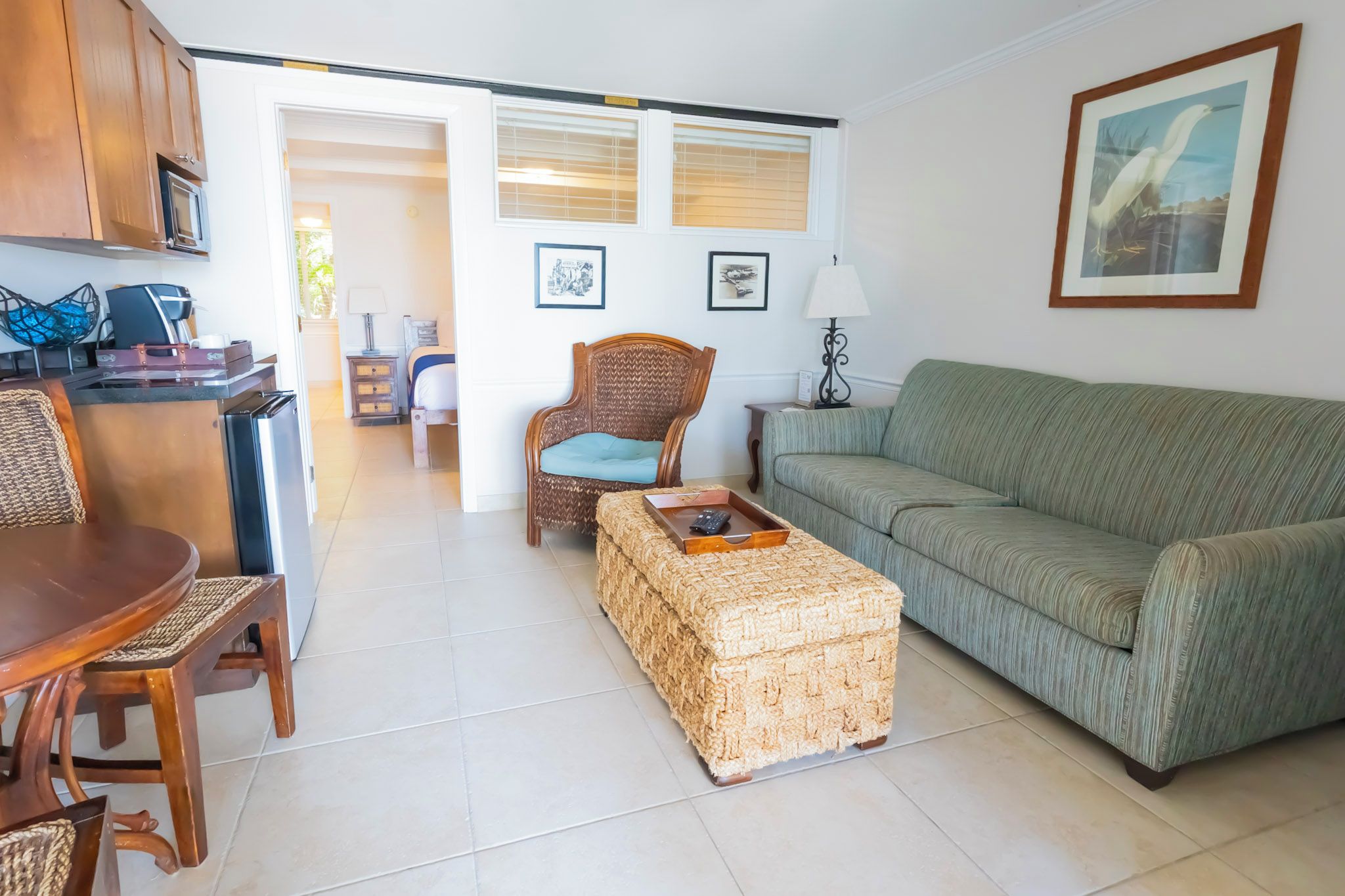 A living room with a sofa, a chair, a dining table, and a kitchen area with cabinets and a microwave.