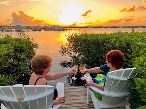 Two people toasting with drinks at a dock with boats in the background. - Coconut Palm Inn (Tavernier)