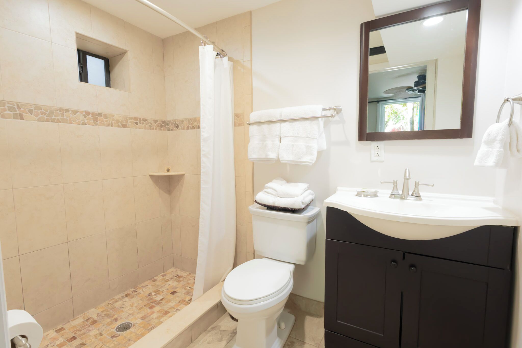 Un baño con ducha, inodoro, lavamanos y espejo.