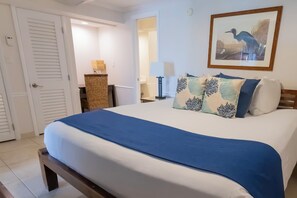 Un dormitorio con cama, almohadas, mesita de noche, lámpara, espejo y puerta.
