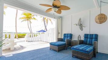 A room with wicker furniture, a ceiling fan, and a view of palm trees.