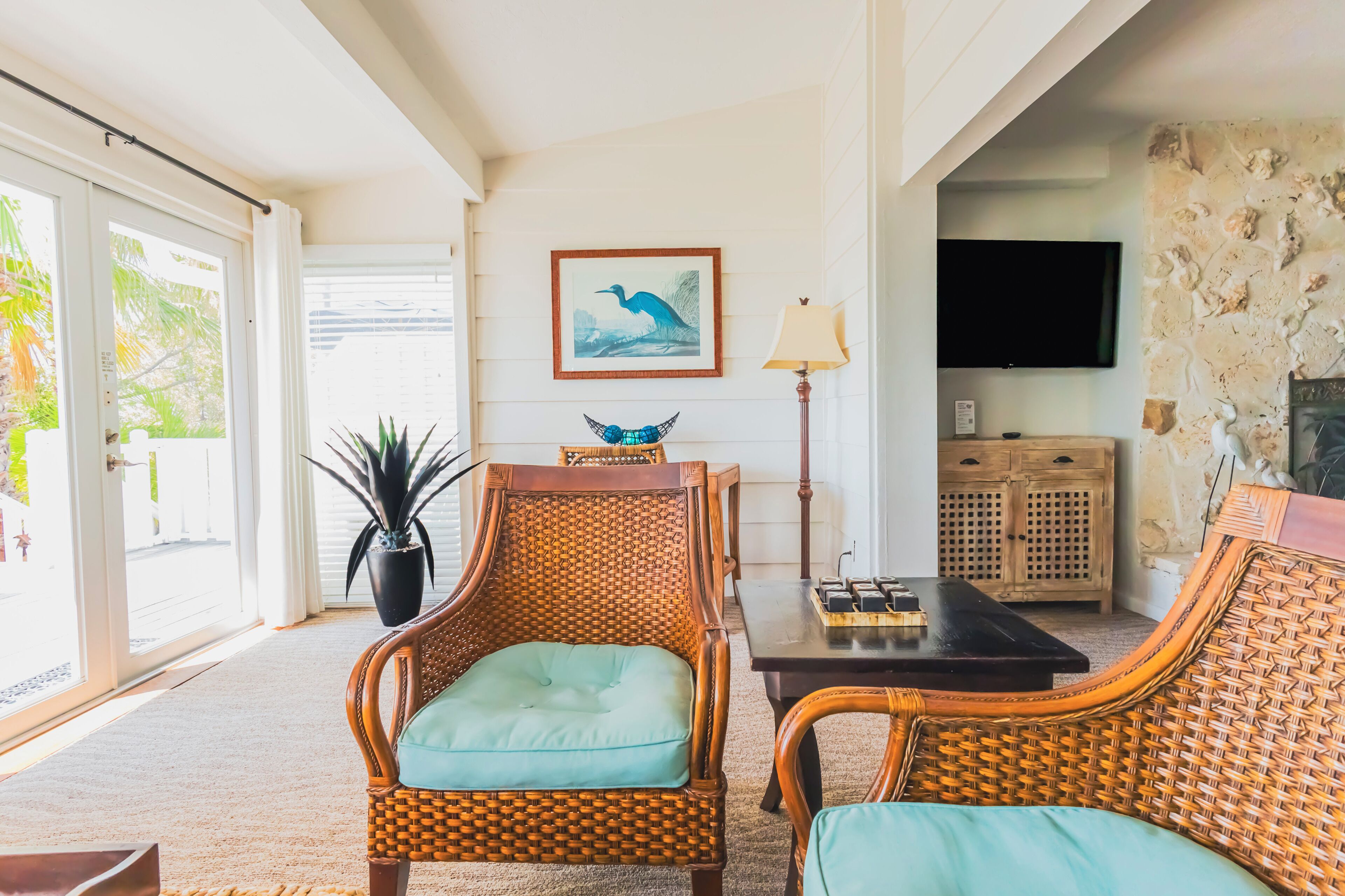 A room with wicker furniture, a television, and a framed picture on the wall.