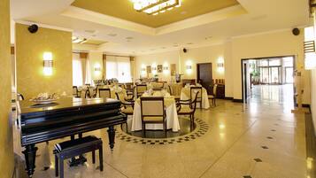 Un hall d’entrée spacieux, agrémenté d’un magnifique piano à queue, de plusieurs tables à manger et de sièges confortables.