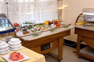 Una barra de desayuno con diferentes opciones de comida y un dispensador de bebidas tipo autoservicio.