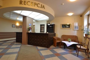 A reception area with a reception desk, seating, and a tiled floor.