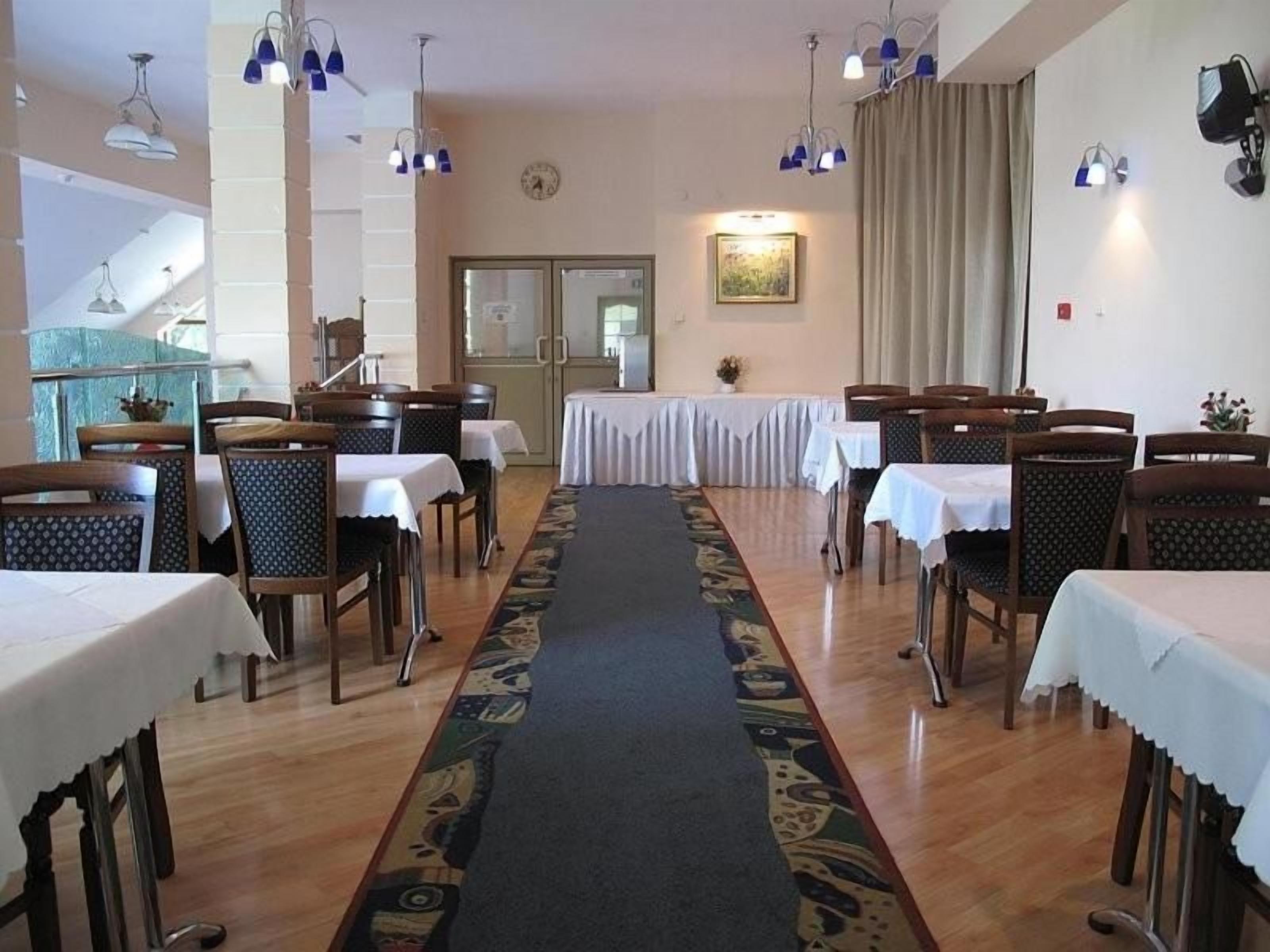 Un espace repas avec des tables et des chaises, une moquette à motifs et des luminaires suspendus.