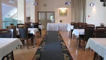 Un espace repas avec des tables et des chaises, une moquette à motifs et des luminaires suspendus.