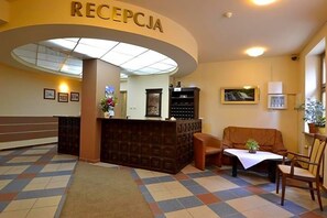 A reception area with a reception desk, a sofa, a table with a plant, and a patterned floor.