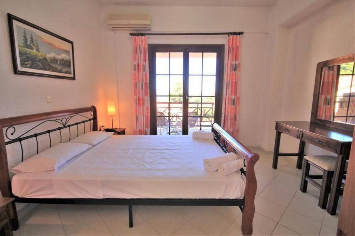 A bedroom with a bed, a desk, a chair, a window with curtains, and a painting on the wall.