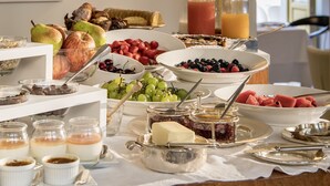 A breakfast buffet with various fruits, pastries, and beverages.