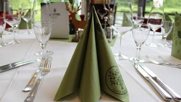 A table set for a meal with a green napkin, silverware, and wine glasses.