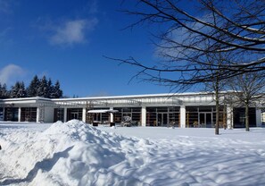 A modern building with large windows and a snow-covered ground.