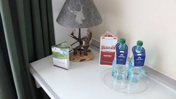 A table with a lamp, a brochure, a decorative tree, and two bottles of water.