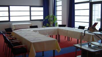 Une salle de conférence avec une longue table, des chaises, un projecteur et une plante.