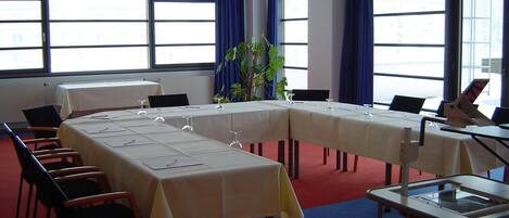 A conference room with a long table, chairs, a projector, and a plant.