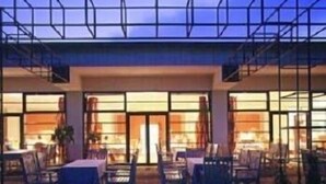 A modern hotel with a glass facade, outdoor seating area, and large windows. - Hotel Rennsteig (Masserberg)