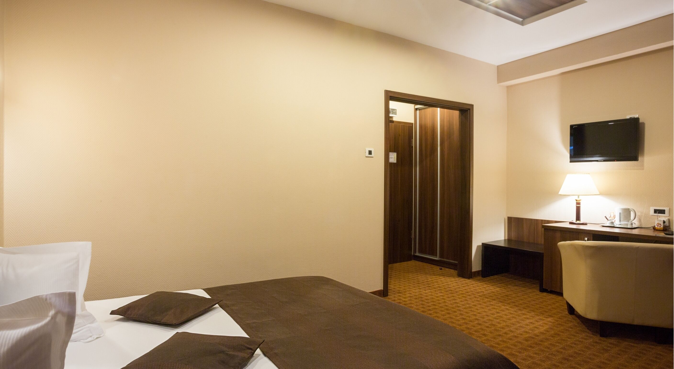 Una habitación de hotel con una cama, un escritorio, una silla, un televisor y una lámpara.