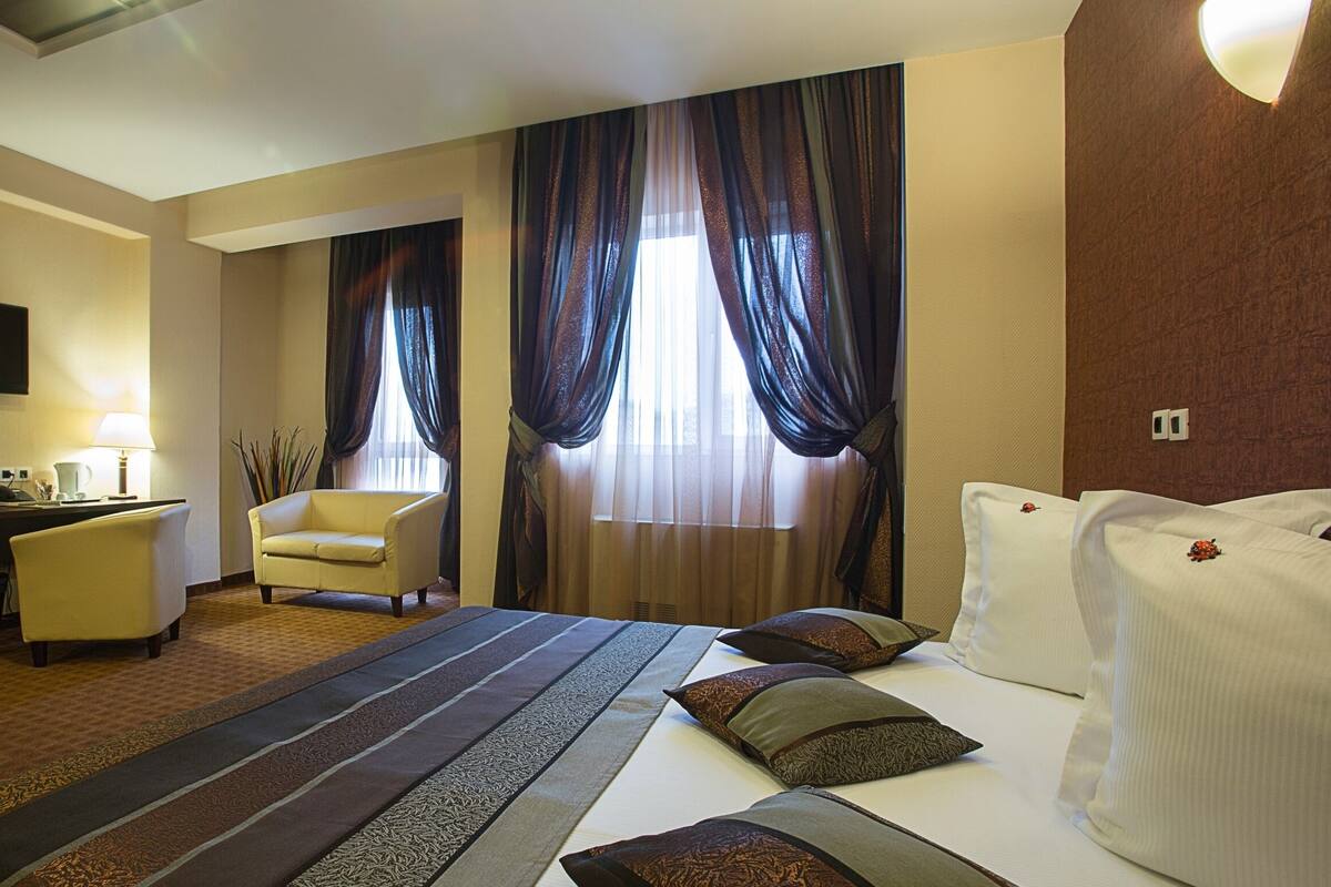 A hotel room with a bed, a desk, a chair, and a TV.