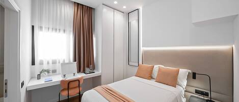 A modern bedroom with a bed, desk, and chair.