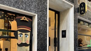 Facciata di un edificio con una grande statua di legno decorata nella finestra, un cartello con su scritto 