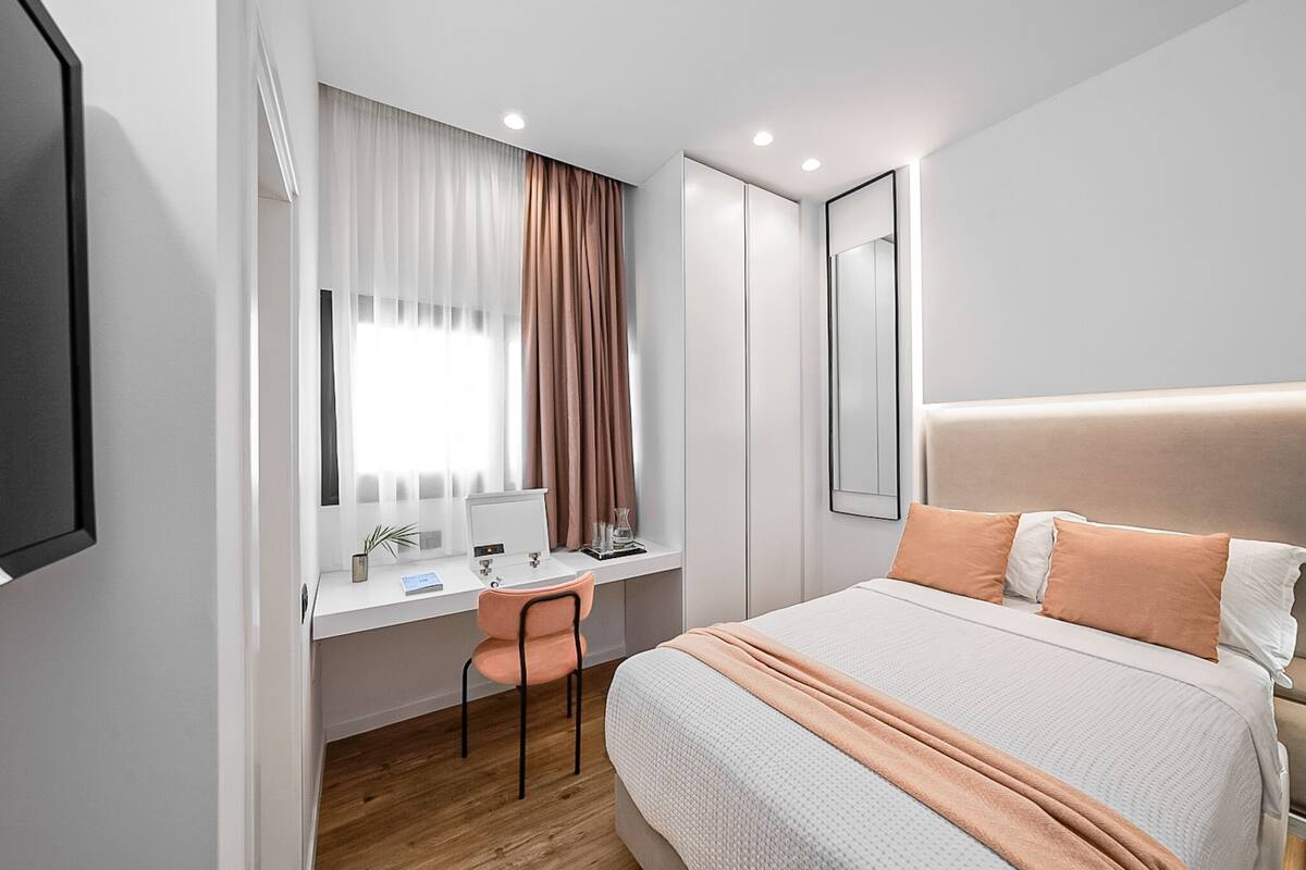 A modern bedroom with a bed, a desk, and a chair.