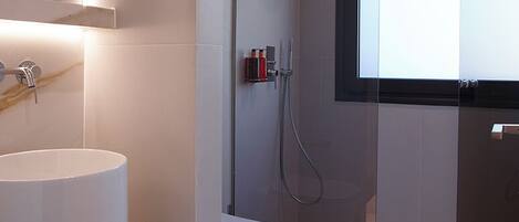 A modern bathroom with a white sink, toilet, and glass-enclosed shower.