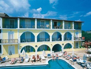 A hotel with a pool area, multiple balconies, and outdoor seating. - Vossos Hotel Apartments (Zakynthos)