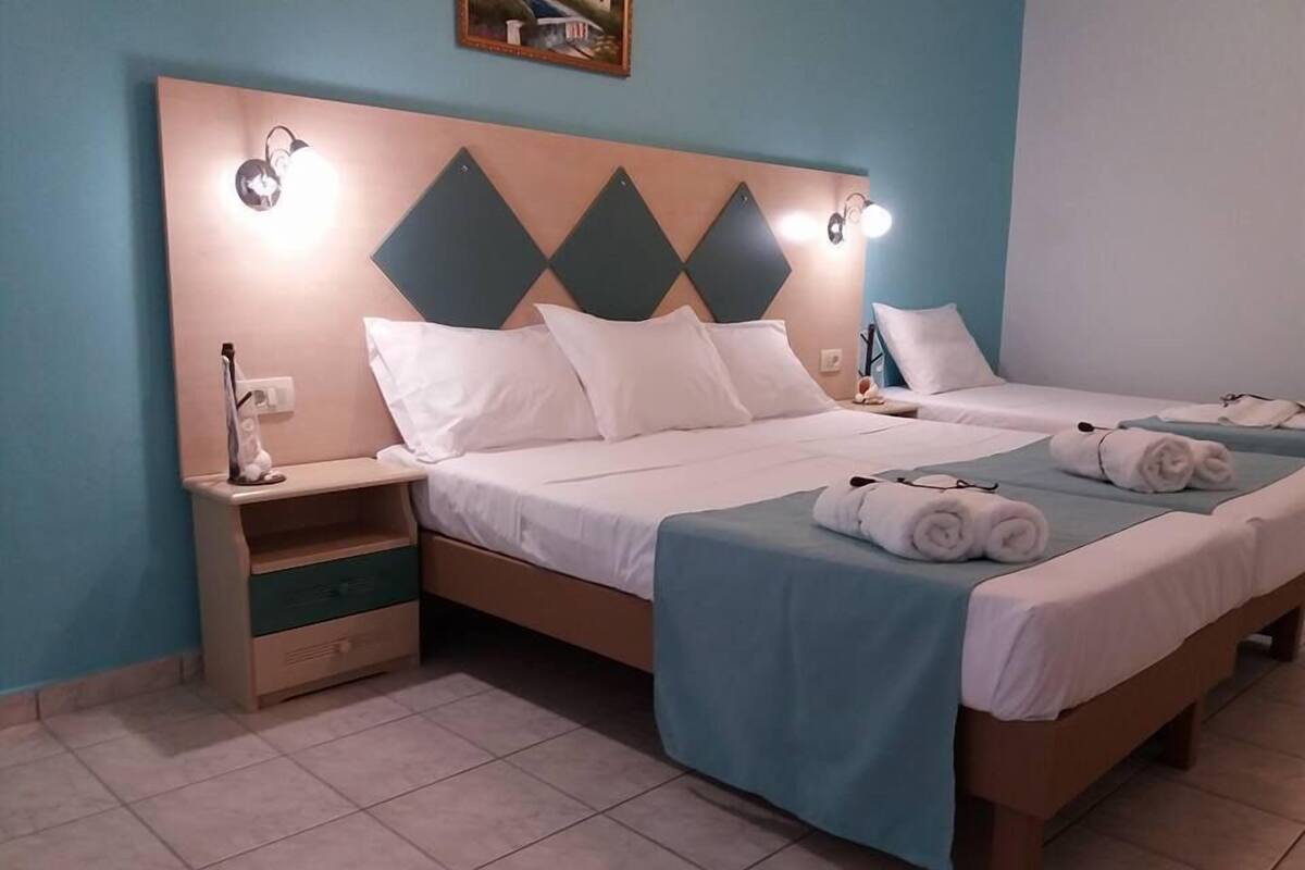 Une chambre d’hôtel avec deux lits, une table de chevet et une étagère fixée au mur.