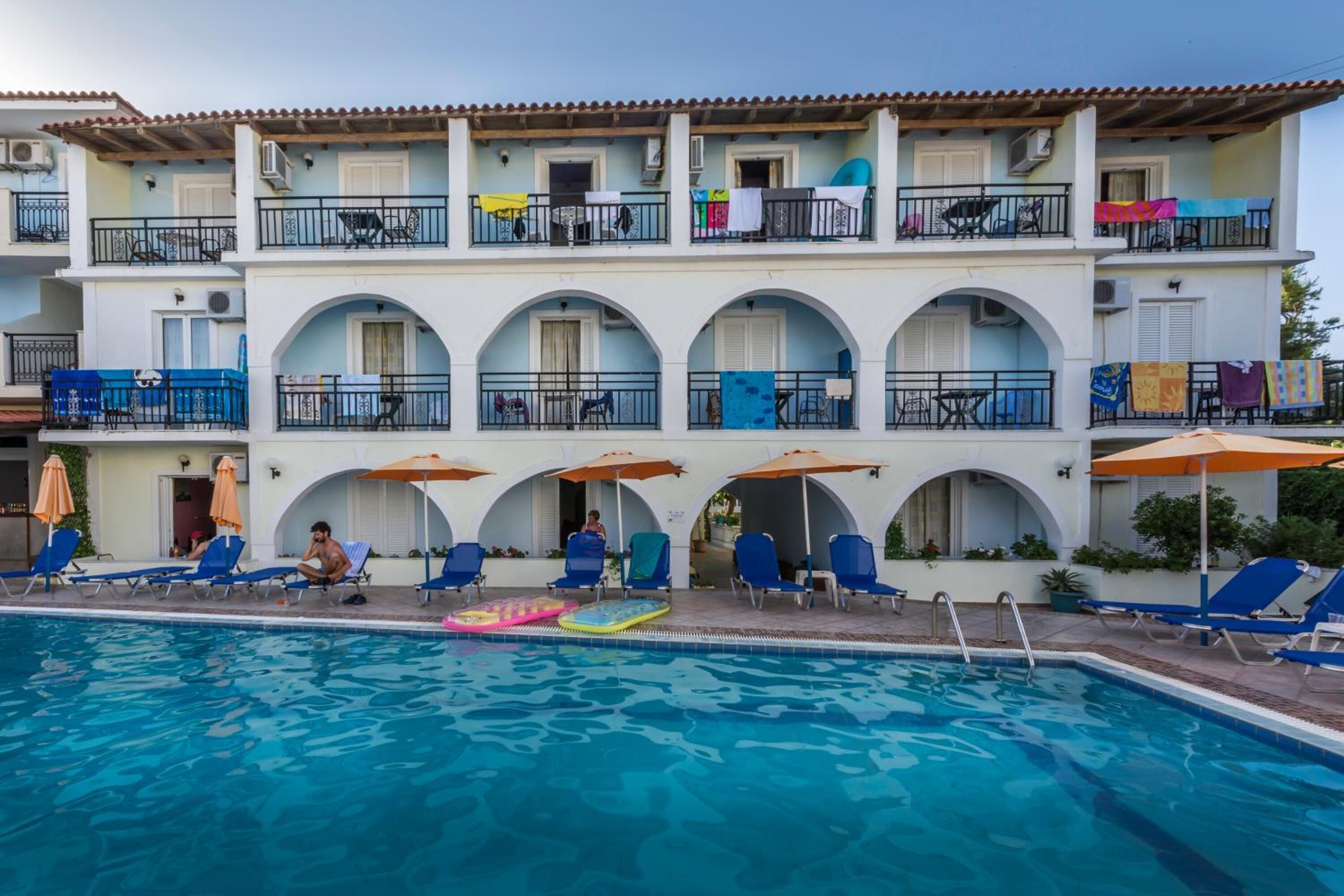 A hotel with a pool area, multiple balconies, and outdoor seating.