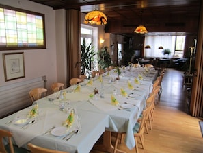 A long dining table set with white tablecloths, chairs, and table settings including plates, glasses, and napkins.
