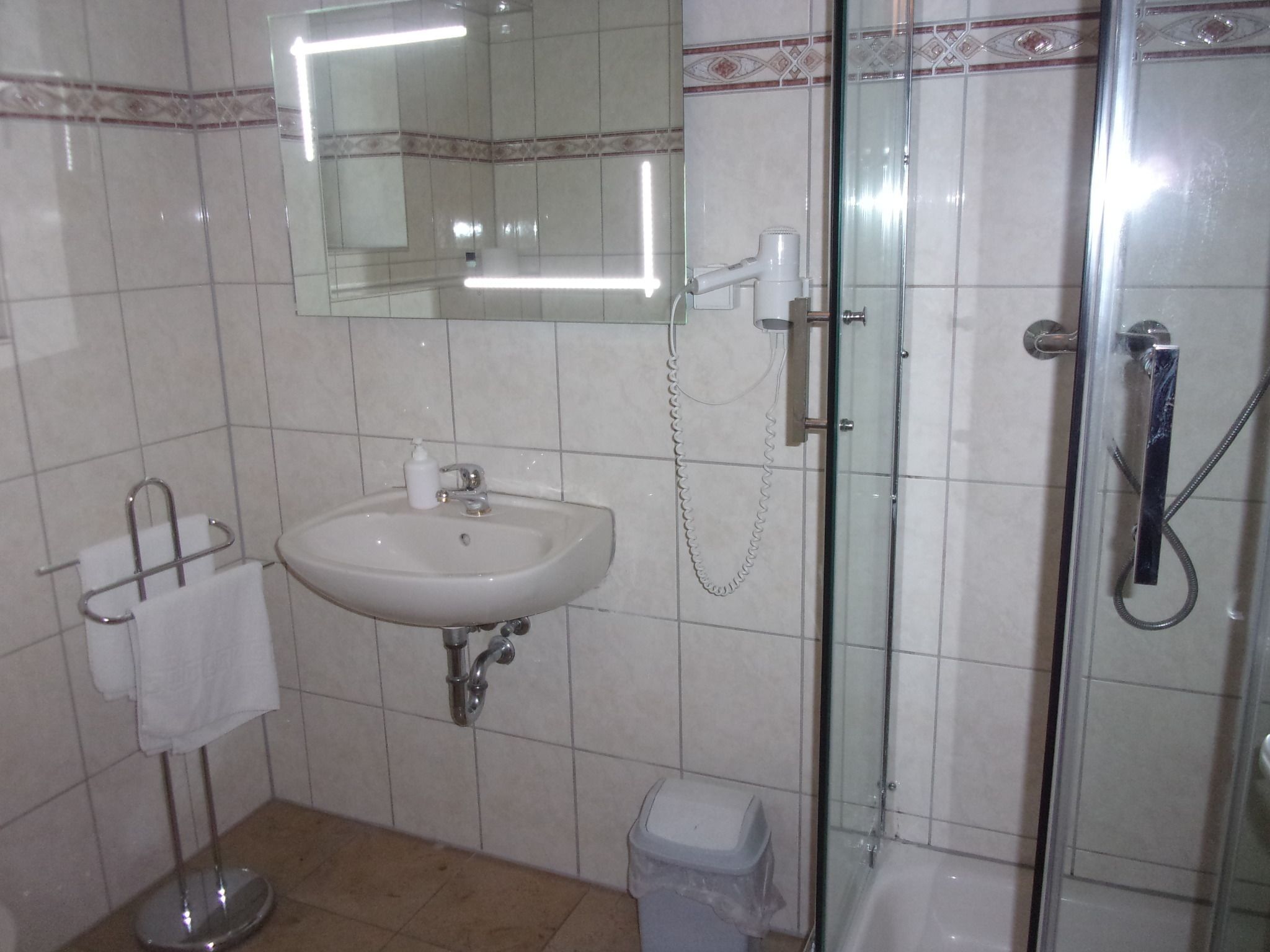 A bathroom with a sink, mirror, and glass-enclosed shower.
