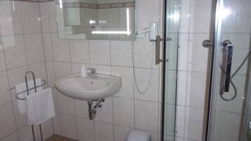 A bathroom with a sink, mirror, and glass-enclosed shower.