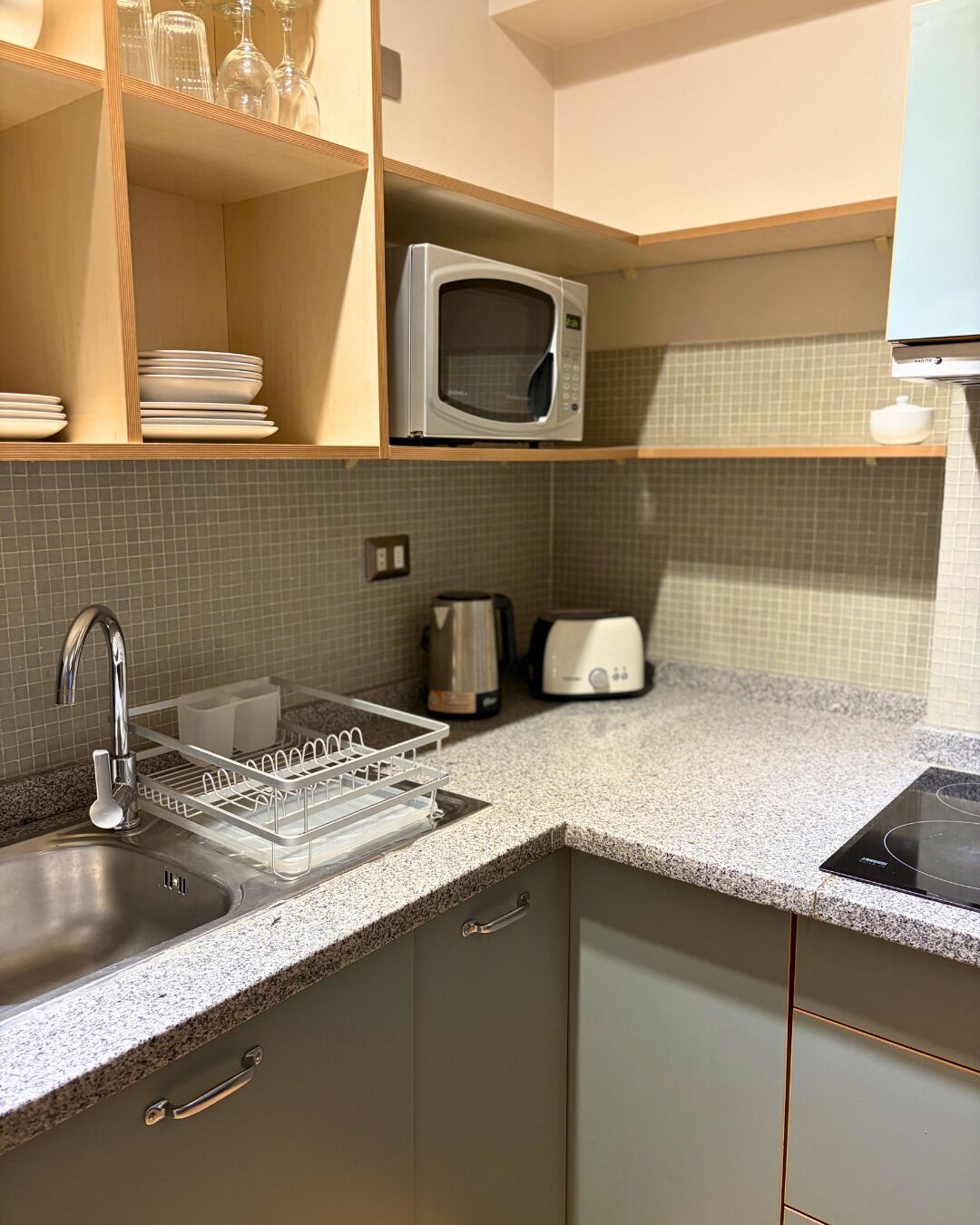 Uma cozinha equipada com micro-ondas, chaleira, torradeira e escorredor de pratos.