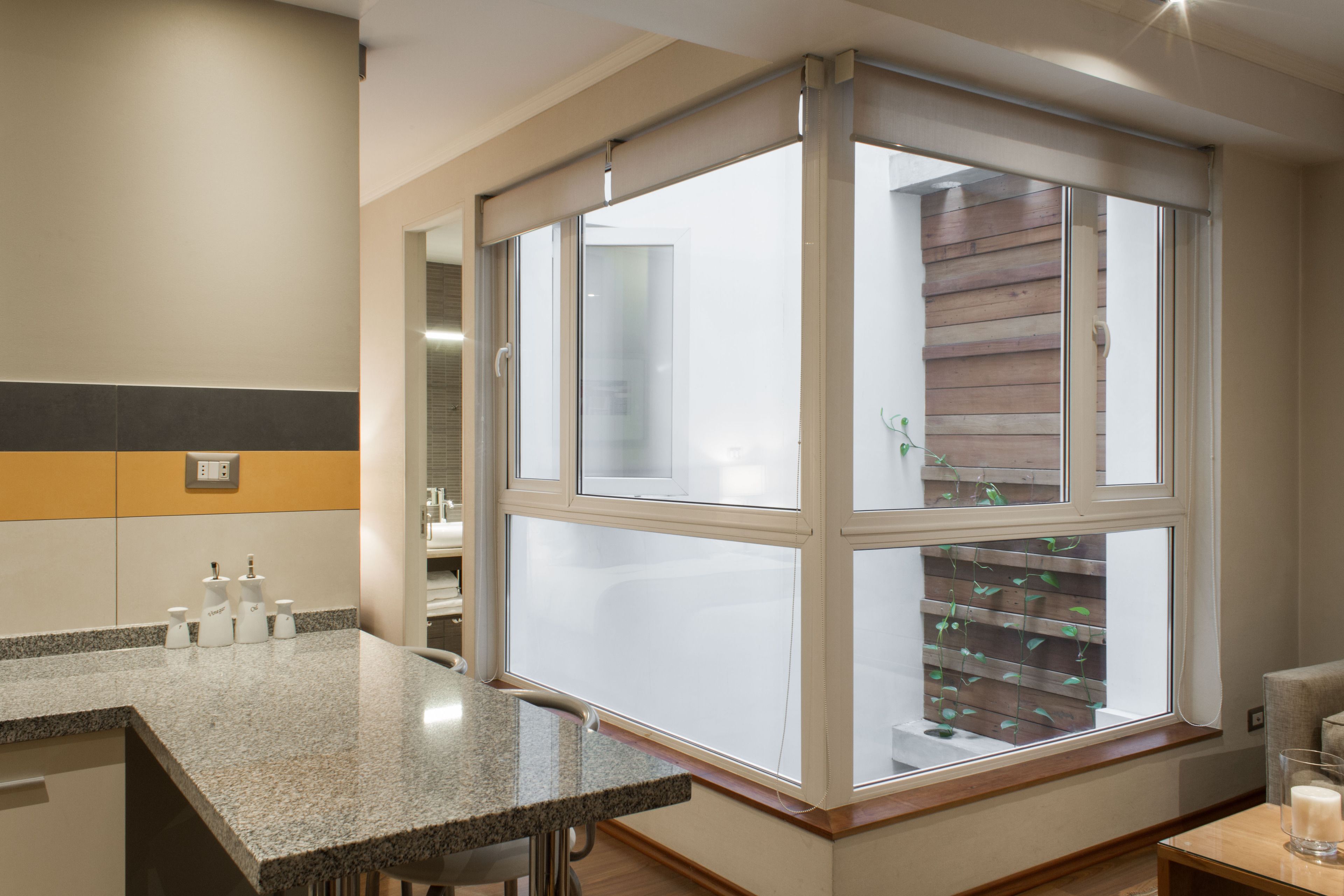 A modern bathroom with a granite countertop, a wooden window sill, and a glass of water on a small table.