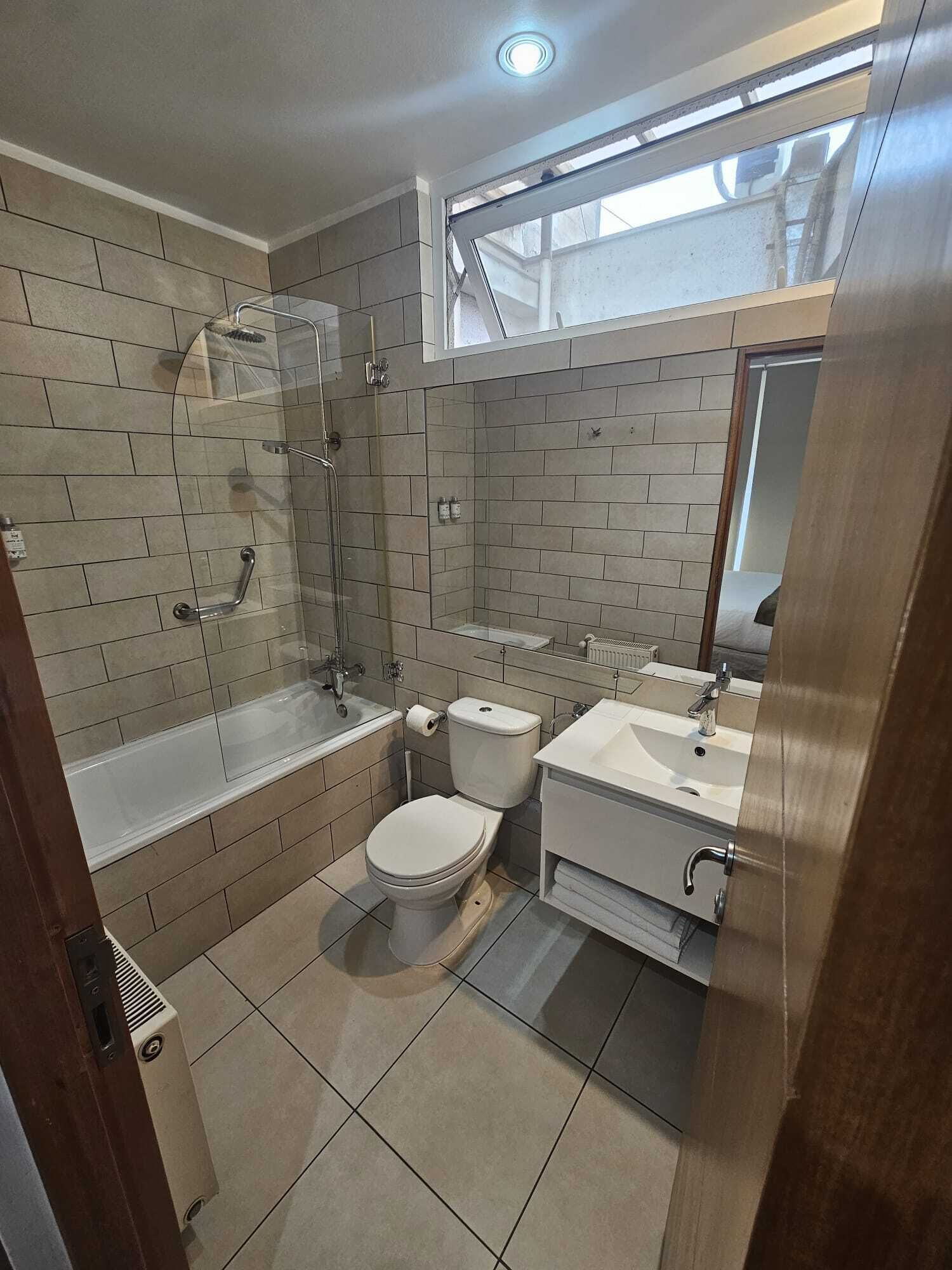 A modern bathroom with a glass shower enclosure, a bathtub, a toilet, and a vanity with a sink.