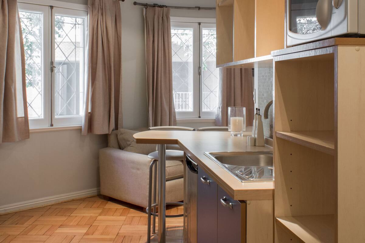 Una cocina moderna con armarios de madera, microondas integrado y una ventana con cortinas.