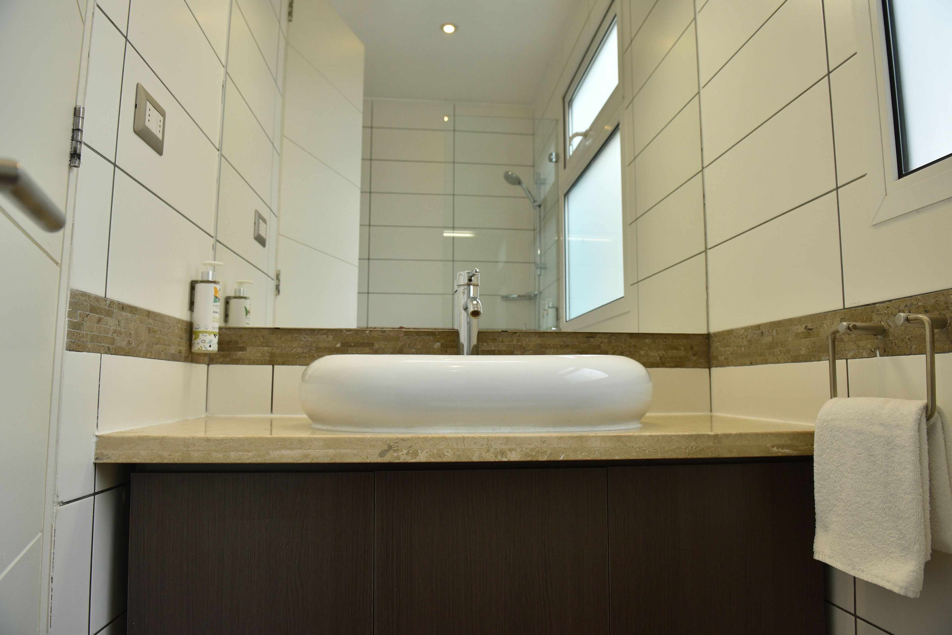 Une salle de bain avec un grand lavabo, des meubles en bois foncé et un miroir au-dessus du lavabo.
