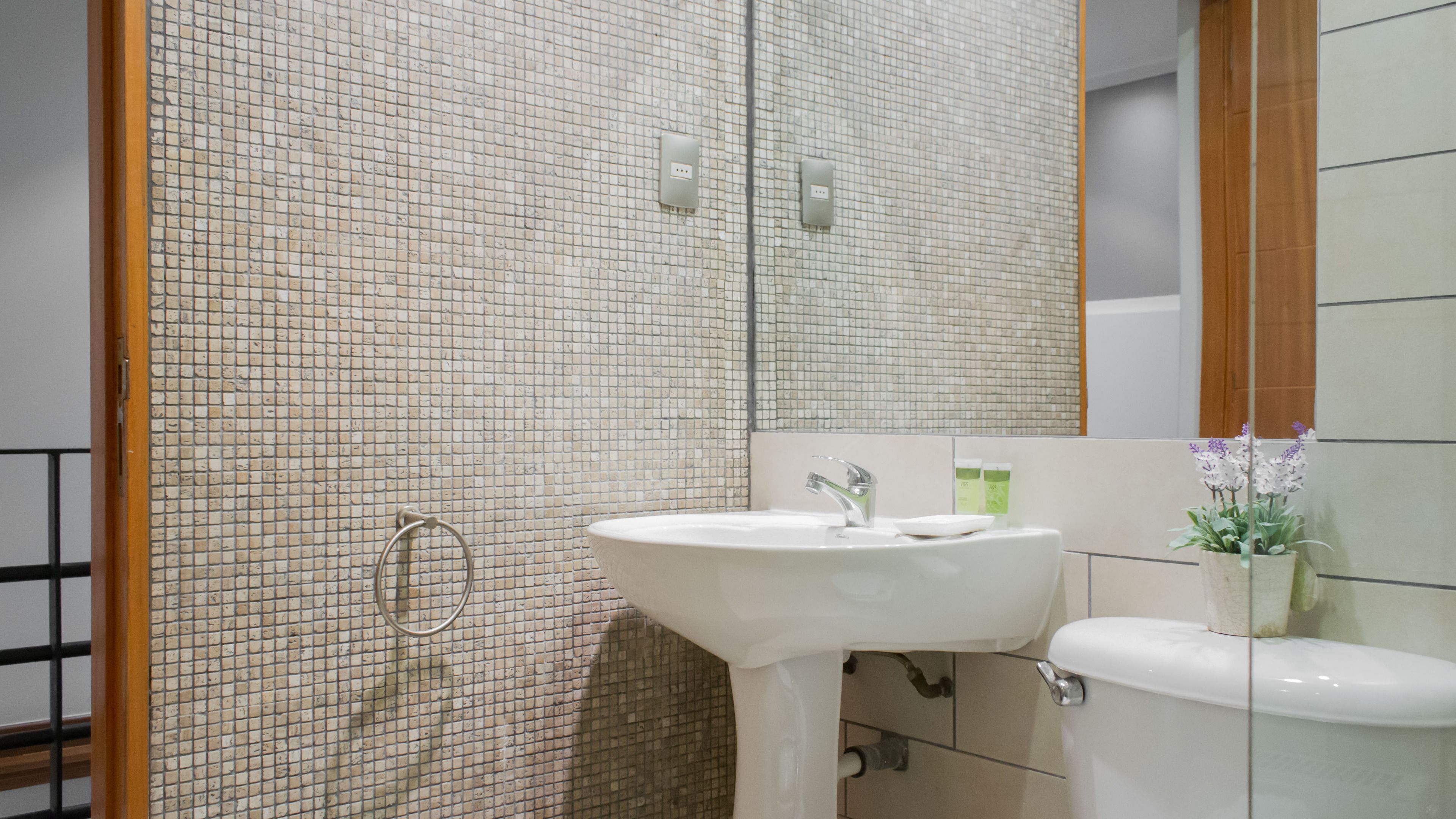 Un bagno con parete piastrellata, lavandino, WC e specchio.