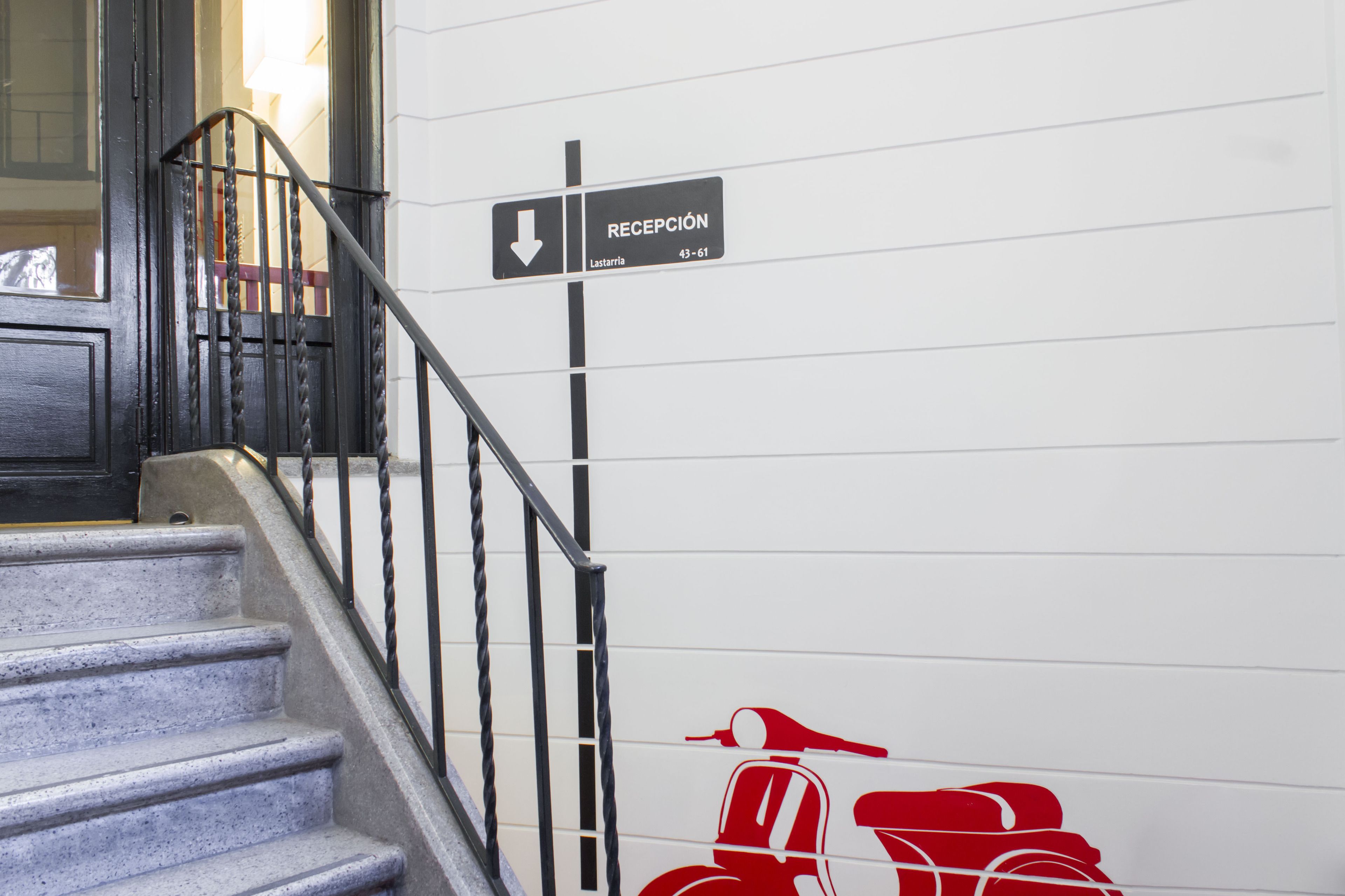 A staircase with a sign pointing to the reception and a red scooter graphic on the wall.