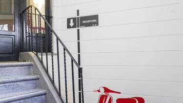 Una scala con un cartello che indica la reception e un'immagine di uno scooter rosso sul muro.