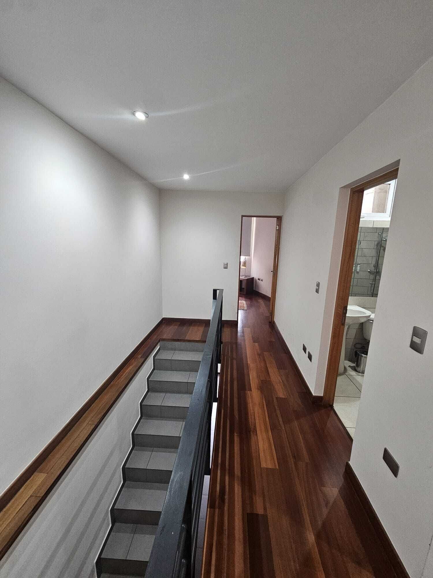 A staircase leading to a bathroom with a shower and toilet visible through an open door.
