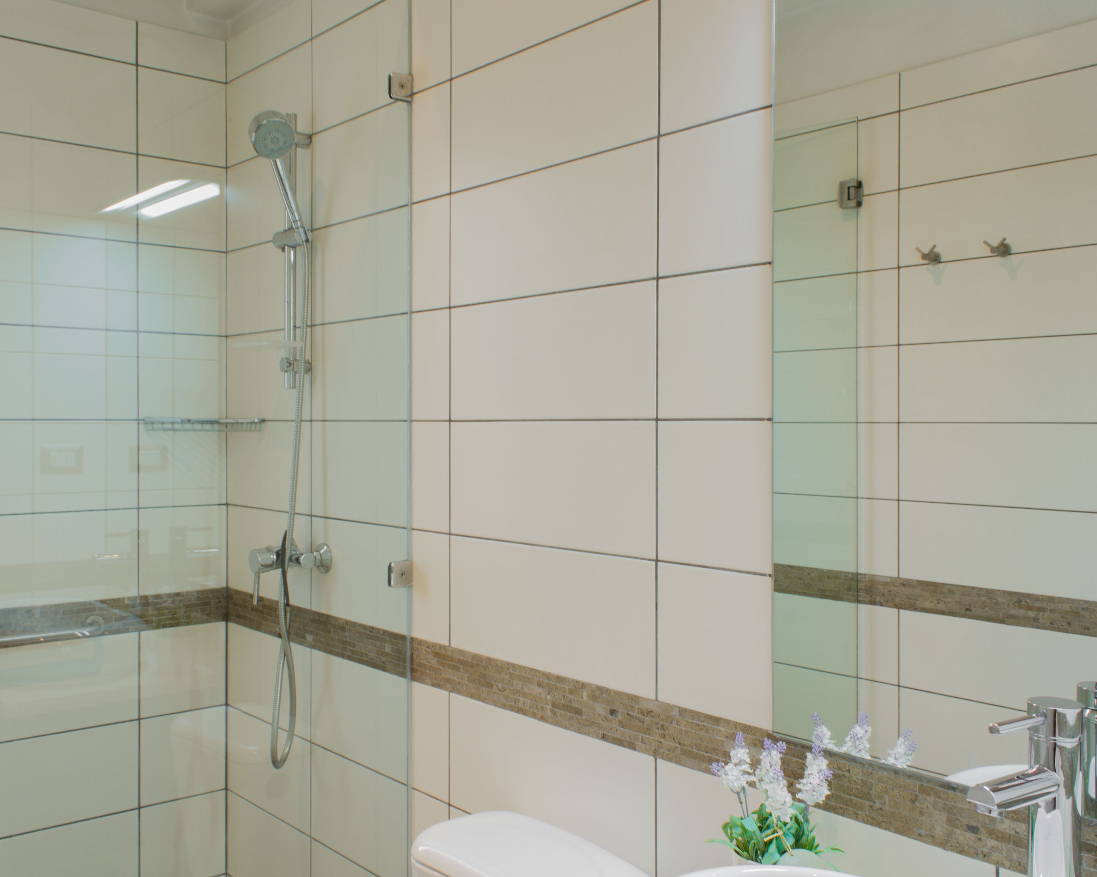 A bathroom with a glass shower enclosure, a white toilet, and a sink with a mirror above it.