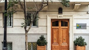 A building with a double wooden door, number 43, and two potted plants on either side. - Lastarria Aparts (Santiago)
