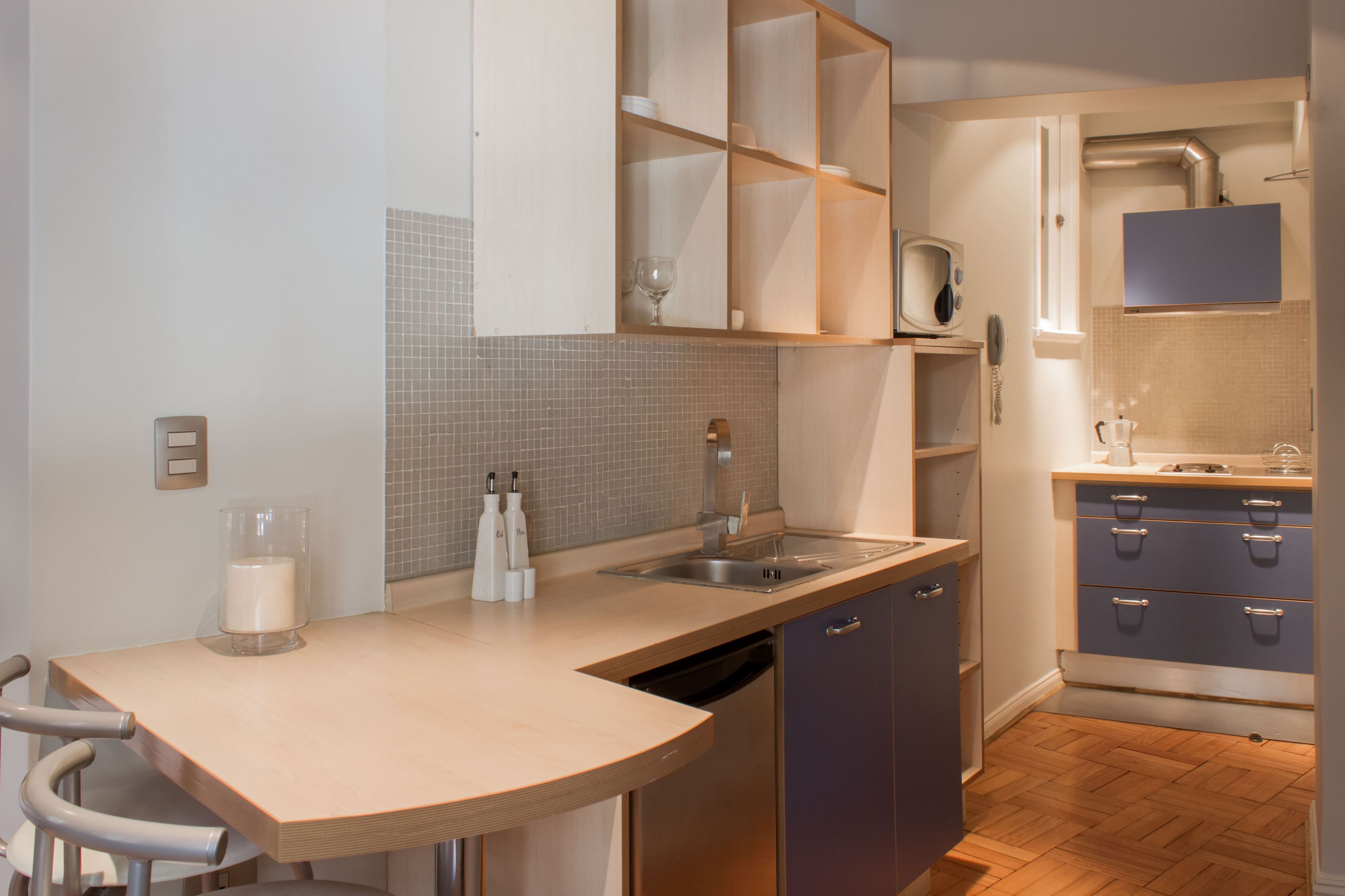 A modern kitchen with a wooden countertop, built-in cabinets, a dishwasher, and a small bar area.