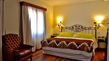 Un dormitorio con una cama grande, un sillón de cuero y dos lámparas de noche.