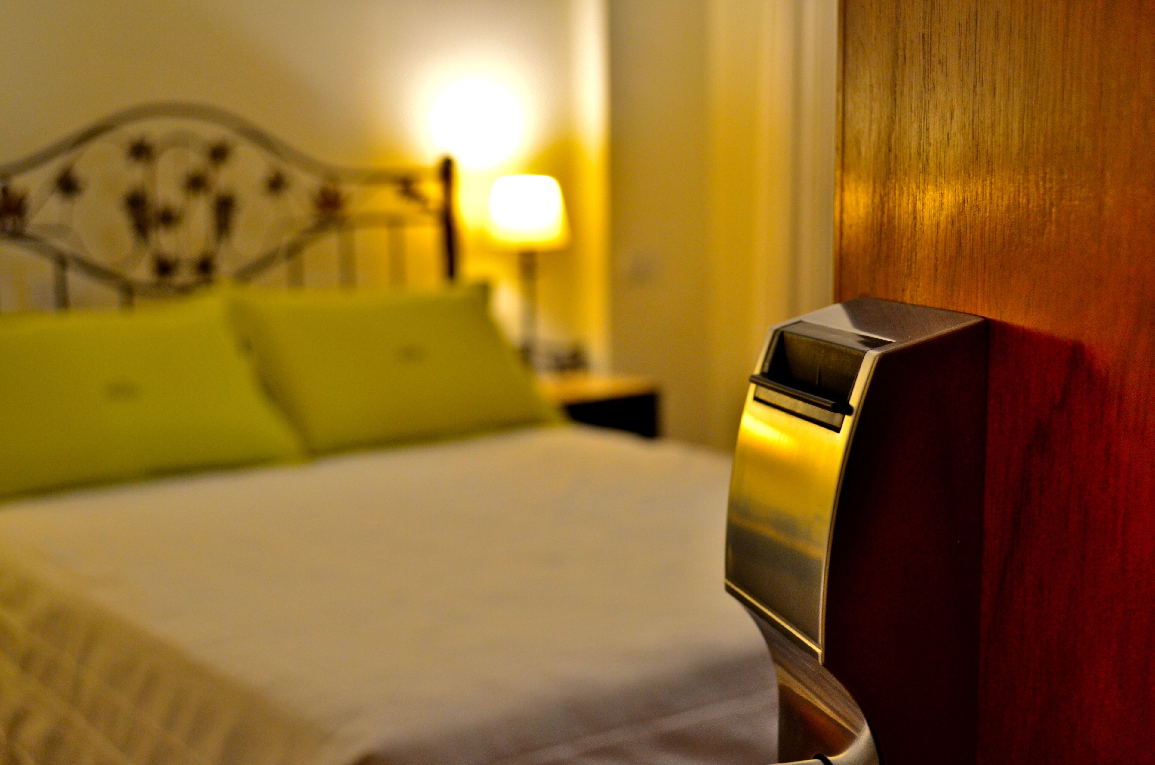 A hotel room with a bed, a nightstand, and a lamp.