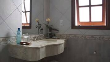 Baño con lavamanos, espejo y ventana.