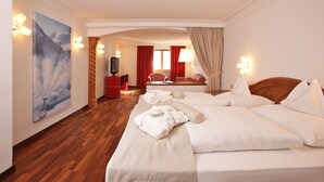 Une chambre d’hôtel avec un grand lit, un plancher en bois, un tableau au mur et un bureau rouge.