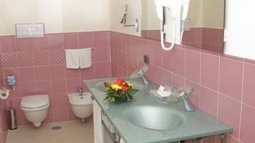 Ein Badezimmer mit einem Waschbecken aus Glas, einer weißen Toilette und einem Bidet.